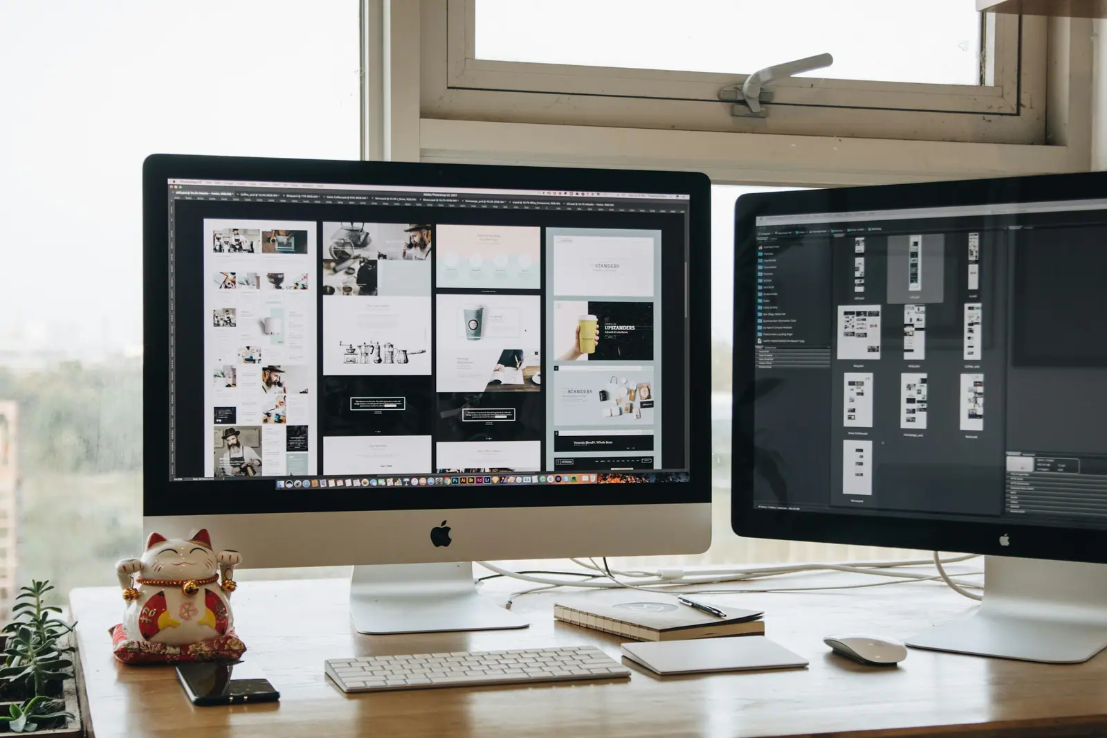 Website layouts displayed on two monitors on a designer's desk