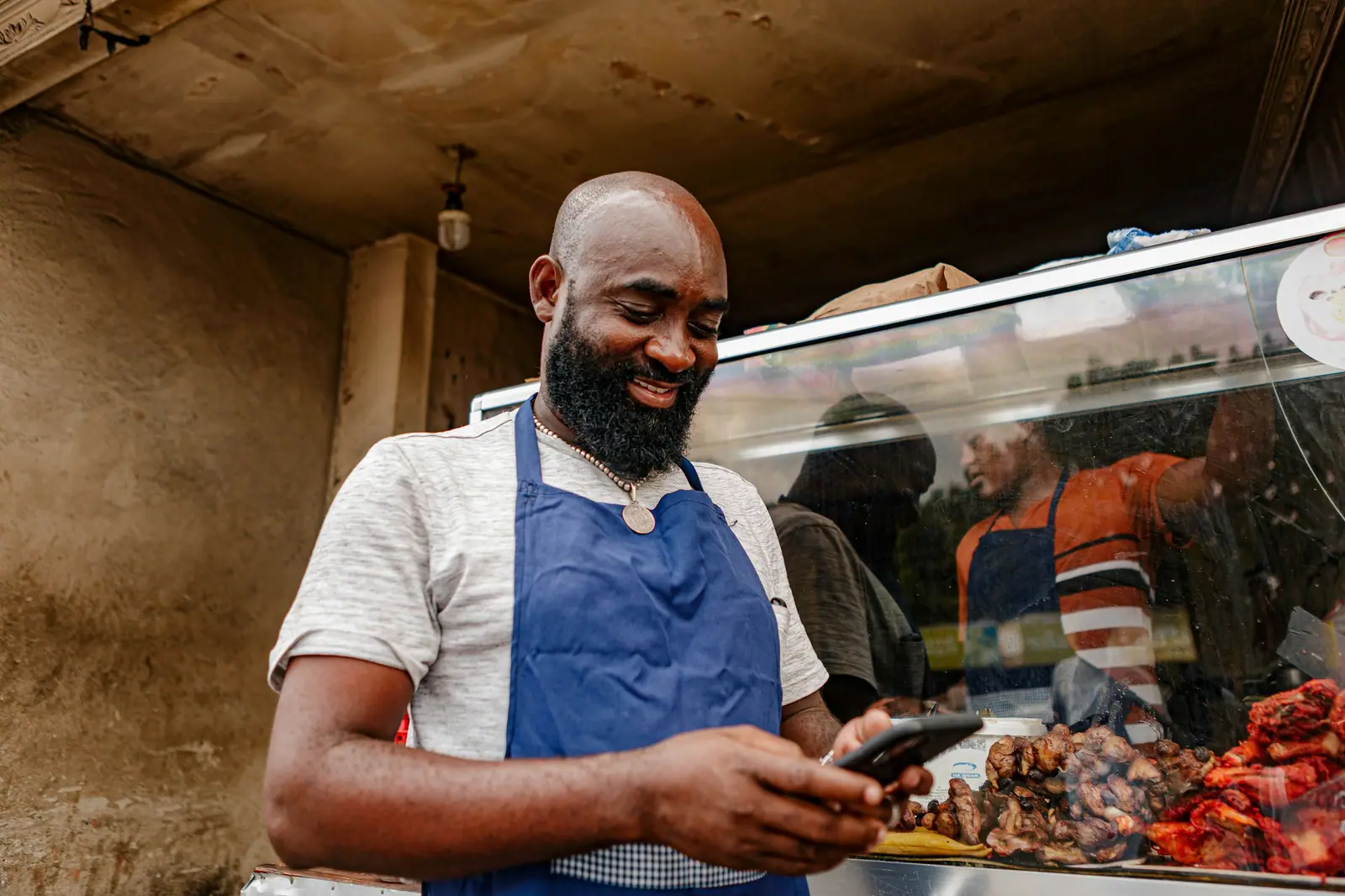 Shop owner smiling at his phone behind the counter